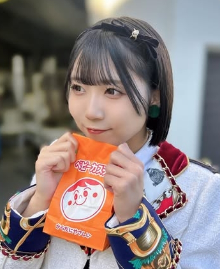 SKE48中坂美祐が金赤緑の衣装でベビーカステラのパッケージを手に持つ様子