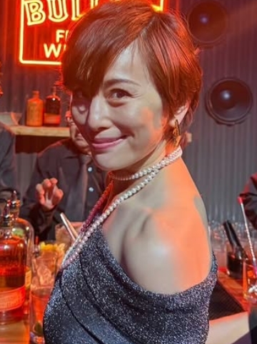 バーのような空間で笑顔を見せる米倉涼子。オフショルダーのスパンコールドレスとパールネックレスが華やかな印象