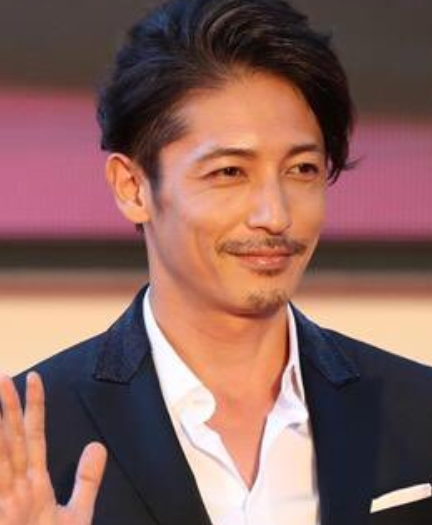 フォーマルなスーツ姿で手を挙げる玉木宏、イベント会場での一コマ