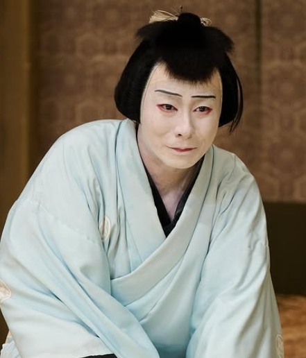 水色の着物と白塗りの化粧を施した中村鶴松さんが歌舞伎の舞台衣装でポーズをとる姿